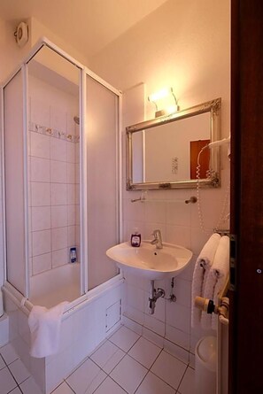 A bathroom with a shower, sink, and mirror.