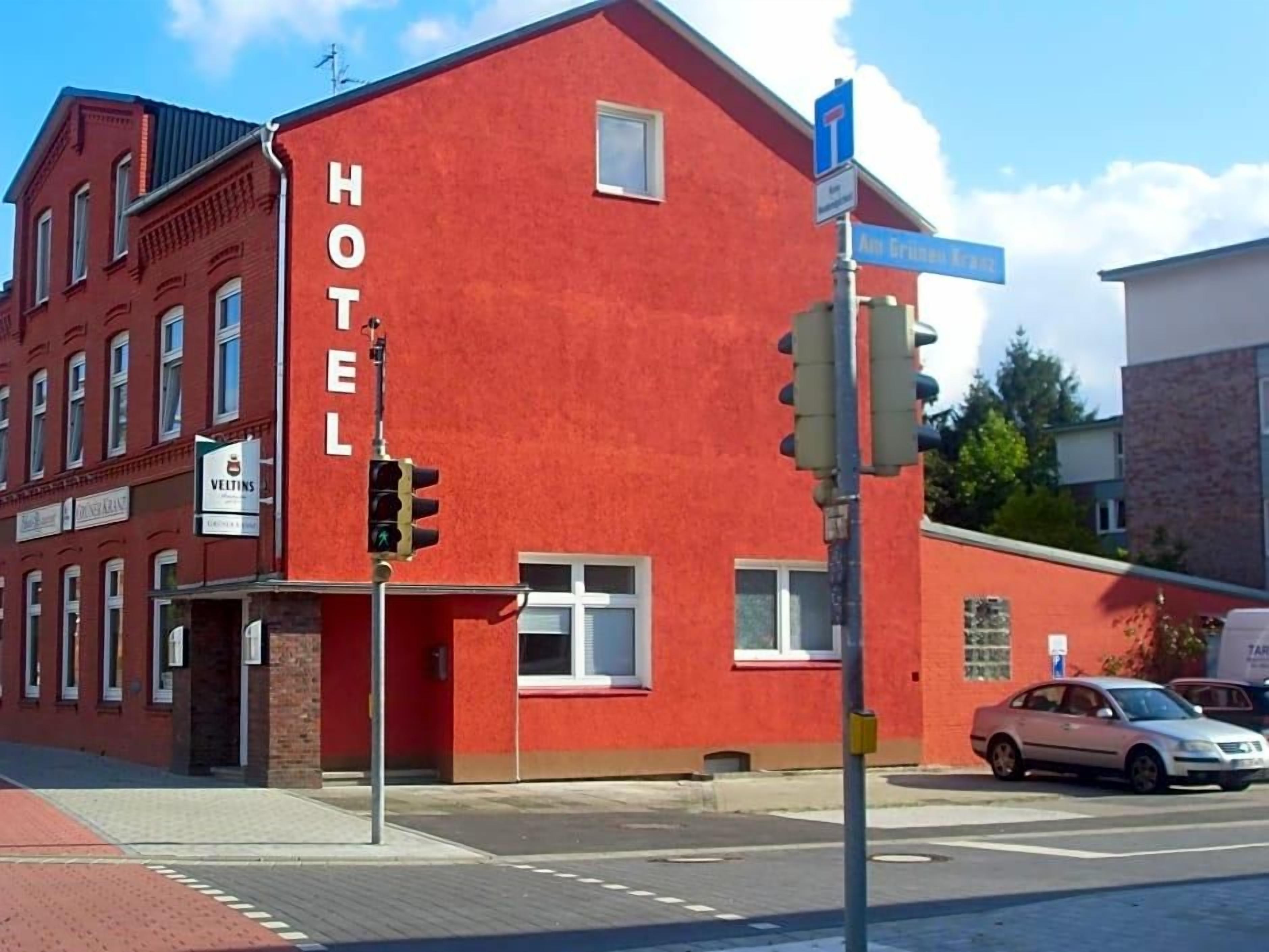 Ein rotes Gebäude mit einem Schild, auf dem 'HOTEL' steht, und einem Straßenschild für 'Ant Grinzenstr.'