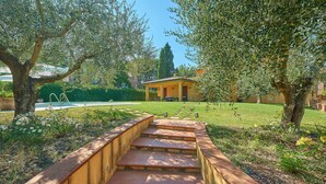 A pathway leading to a building with a yellow facade, surrounded by trees and a grassy area. - Villa Pali (Marsciano)