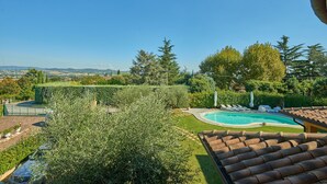 A pool with lounge chairs, a view of the countryside, and a tiled roof. - Villa Pali (Marsciano)