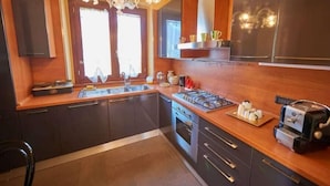 A modern kitchen with dark cabinets, a stainless steel stove, and a built-in oven. - Villa Pali (Marsciano)