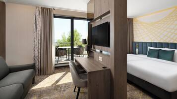 Habitación de hotel con cama, televisor montado en la pared, escritorio con silla y vista al exterior.