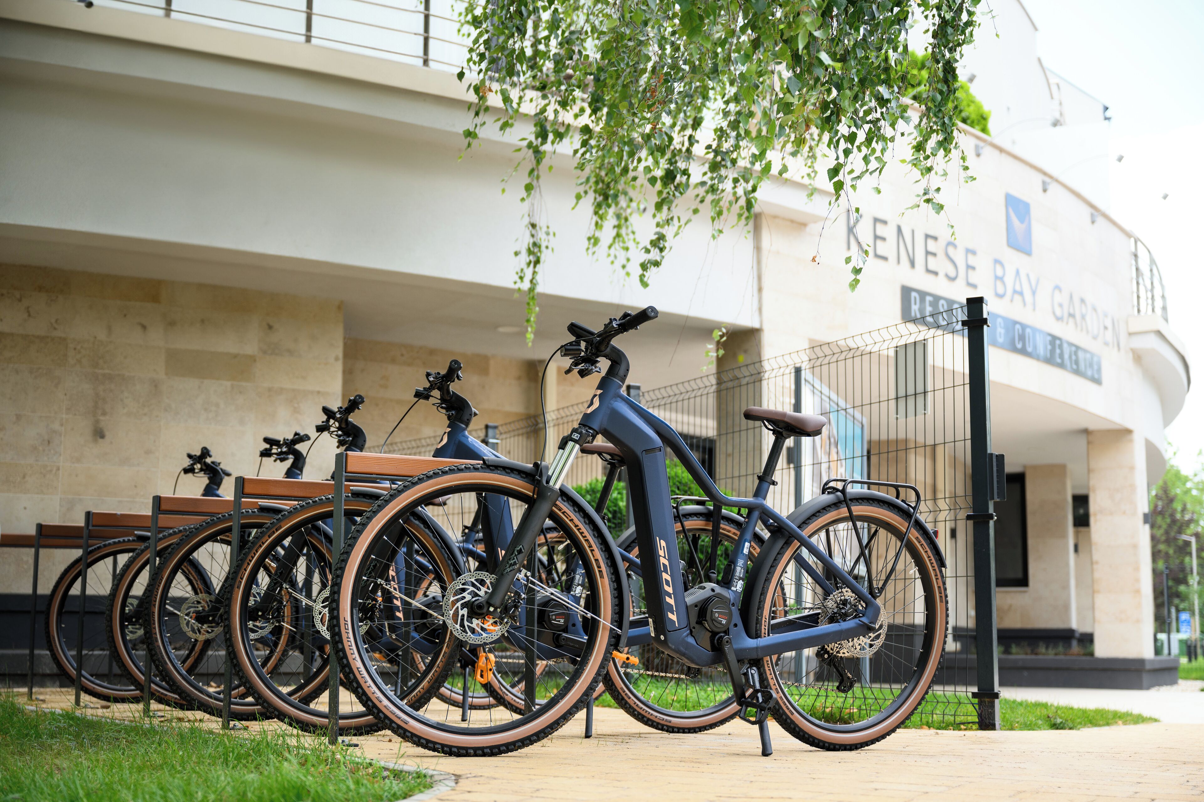 Diverse biciclette parcheggiate di fronte a un edificio con un cartello che riporta la scritta "KENNSE BAY GARDEN".