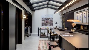 Un intérieur moderne avec un plafond haut, un coin repas et une vue sur le paysage urbain grâce à de grandes fenêtres.