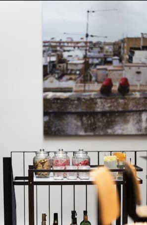 A bar area with a cityscape view, a shelf with jars and bottles, and a metal railing.