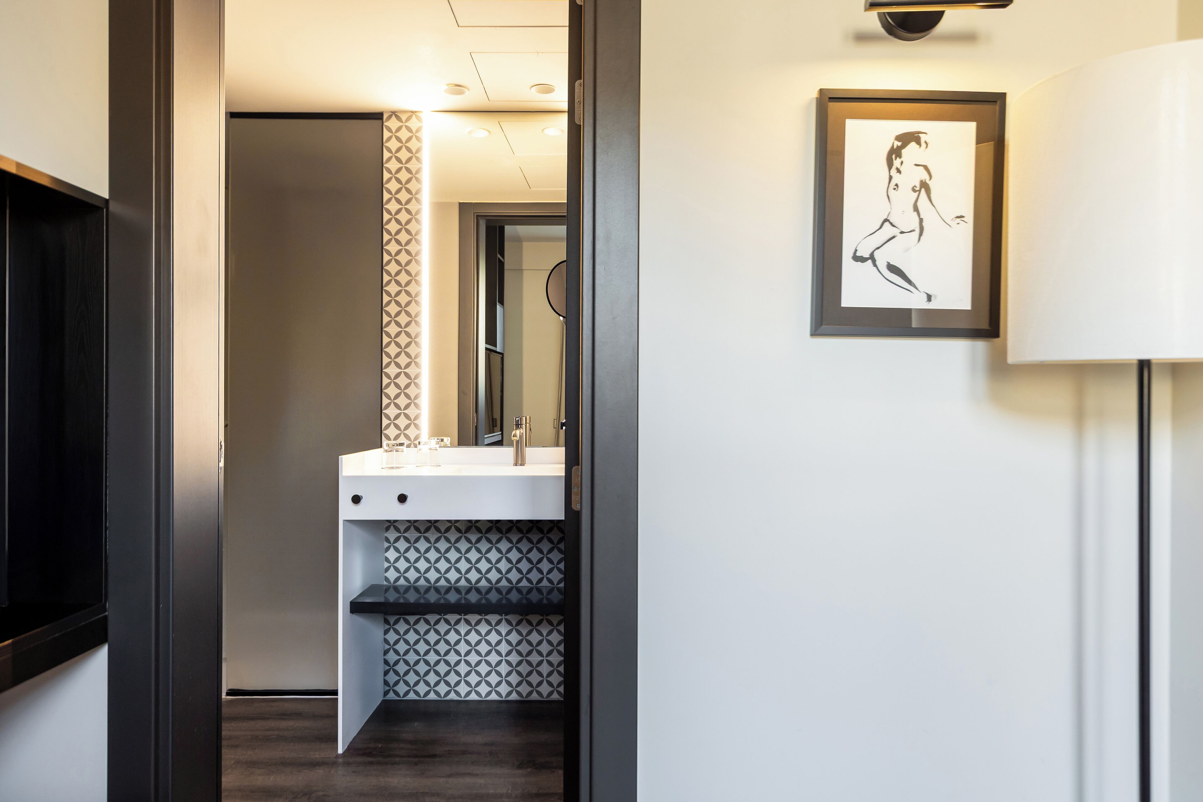 A modern bathroom with a white sink, a mirror, and a patterned tile backsplash.