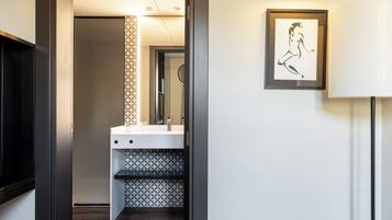 A modern bathroom with a white sink, a mirror, and a patterned tile backsplash.