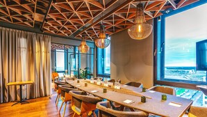 A conference room with a long table, chairs, and a view of the city through large windows. - Four Elements Hotel Amsterdam (Amsterdam)