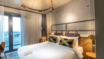 Habitación de hotel con una cama grande, vistas a la ciudad, un balcón y un diseño moderno.