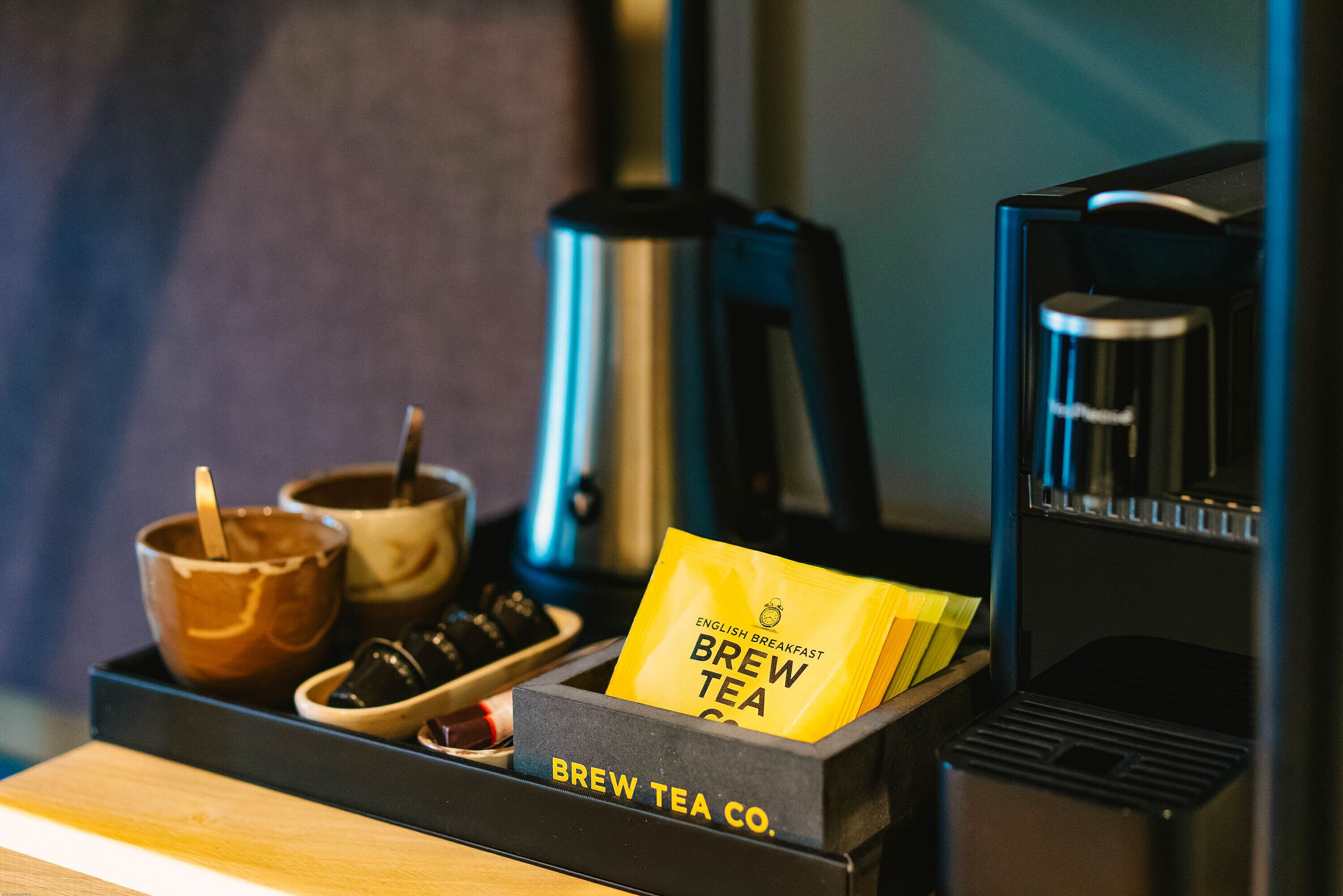 A coffee machine, a kettle, and a tray with a coffee cup and a tea bag.