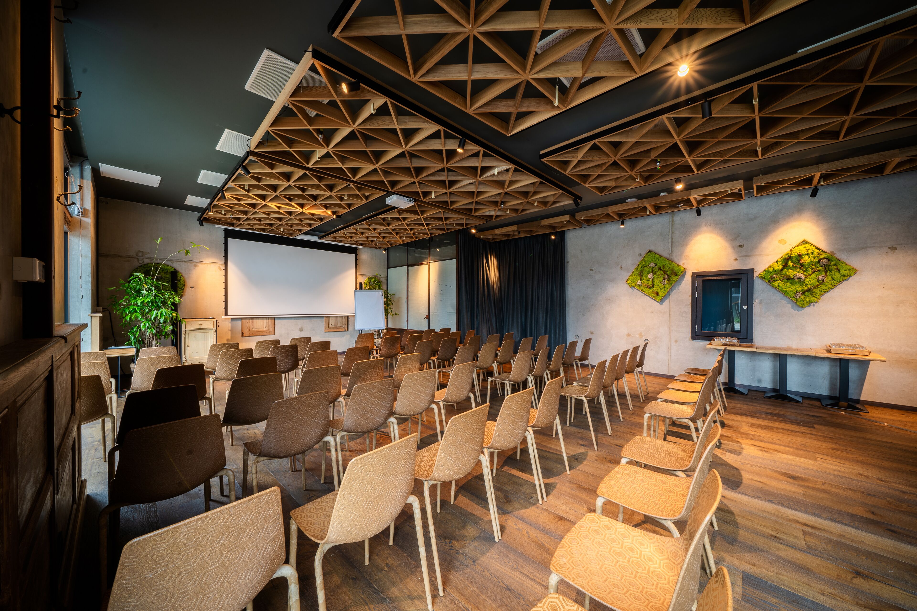 A conference room with rows of chairs, a projector screen, and a wooden ceiling.