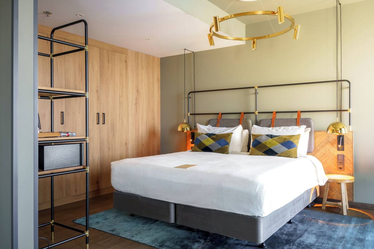 A modern hotel room with a bed, a desk, and a wardrobe.