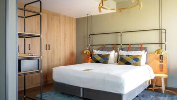 A modern hotel room with a bed, a desk, and a wardrobe.