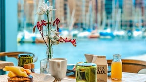A dining table with a meal, a vase with flowers, a milk carton, and a glass of orange juice. - Four Elements Hotel Amsterdam (Amsterdam)