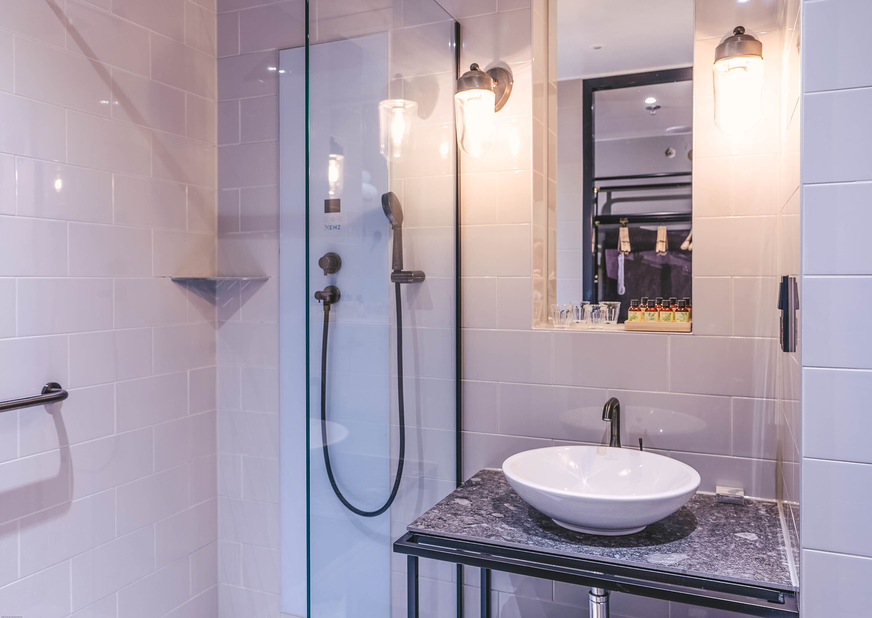 A modern bathroom with a glass-enclosed shower, a white sink, and a mirror above the sink.