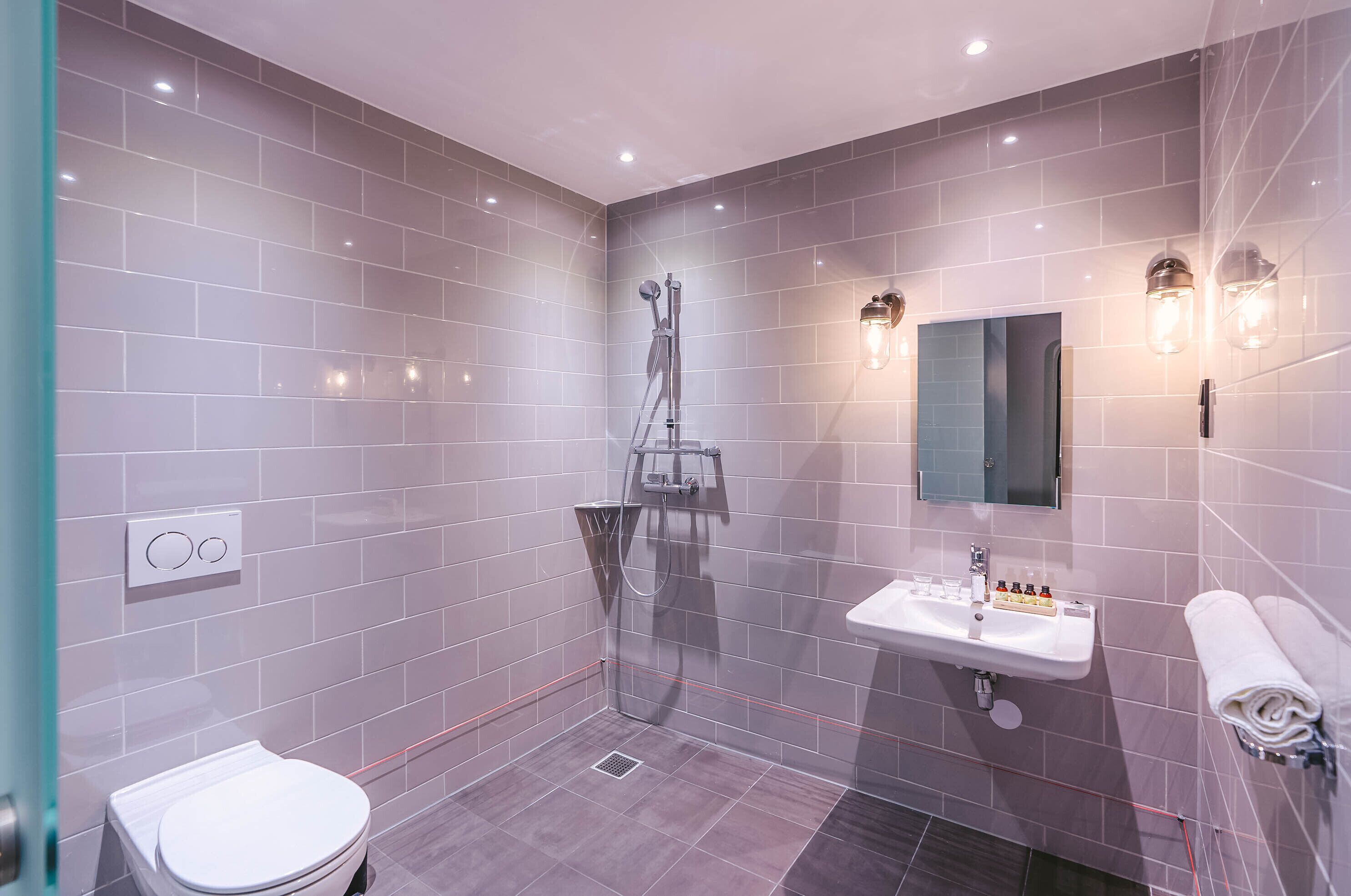 Een moderne badkamer met toilet, douche en wastafel.