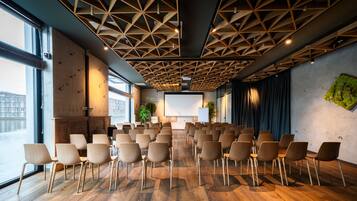 Un salón de conferencias con techo de madera, ventanas amplias y una pantalla de proyector.