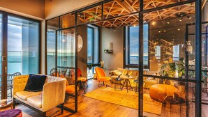 A spacious living area with large windows, a wooden floor, and modern furniture. - Four Elements Hotel Amsterdam (Amsterdam)