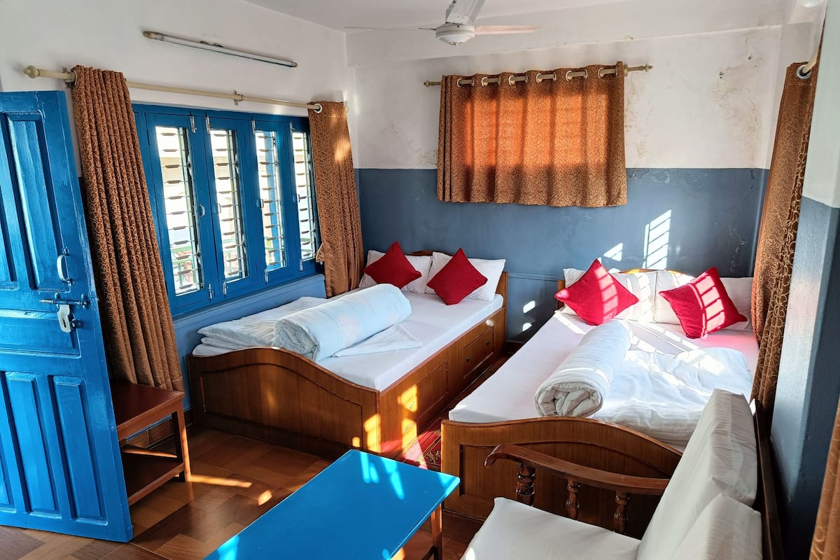 A room with two wooden beds, a blue table, and a blue door.