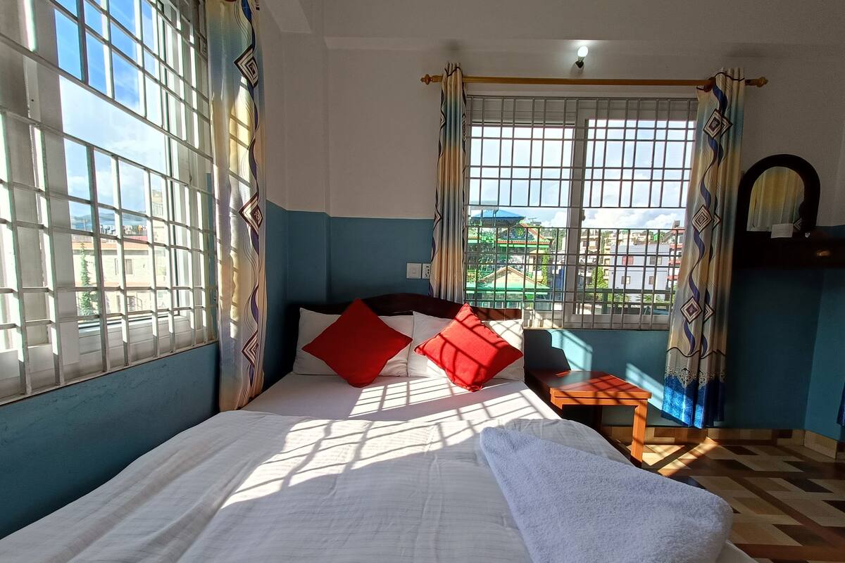 A room with a bed, a small table, and a window with curtains.