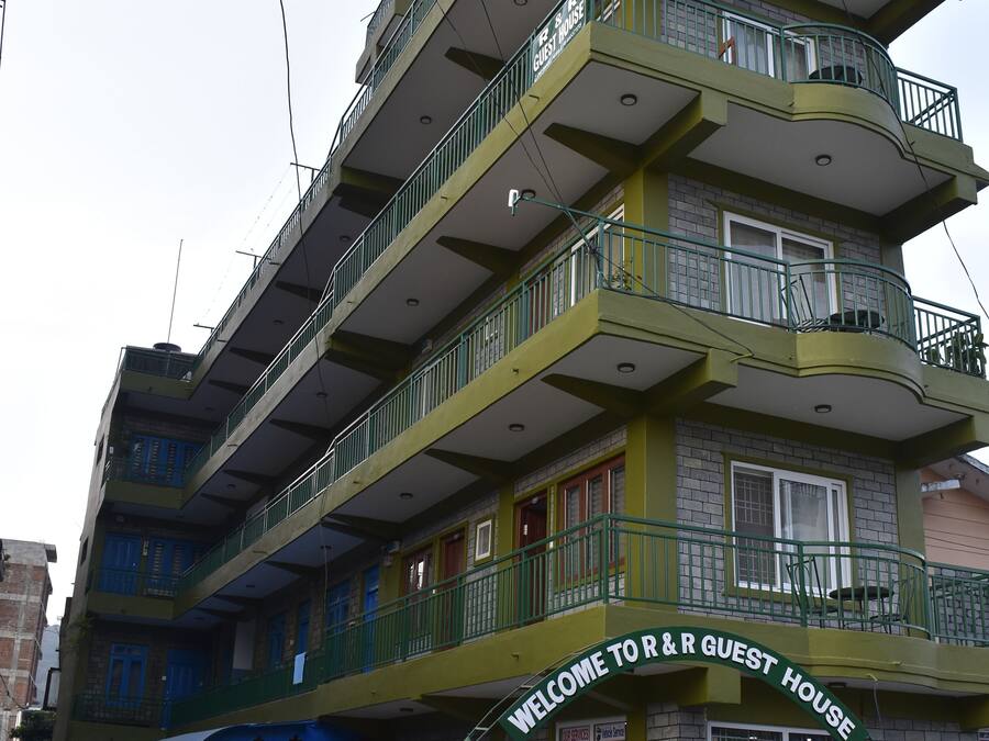 A multi-story guest house with balconies and a sign reading "Welcome to R&R Guest House."