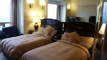 Habitación de hotel con dos camas, un escritorio, una silla y un espejo grande.
