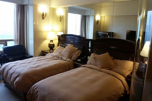 Habitación de hotel con dos camas, un escritorio, una silla y un espejo grande.