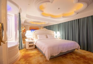 Une chambre d’hôtel avec un grand lit, une table de chevet avec une lampe, un miroir et une salle de bain avec une baignoire.