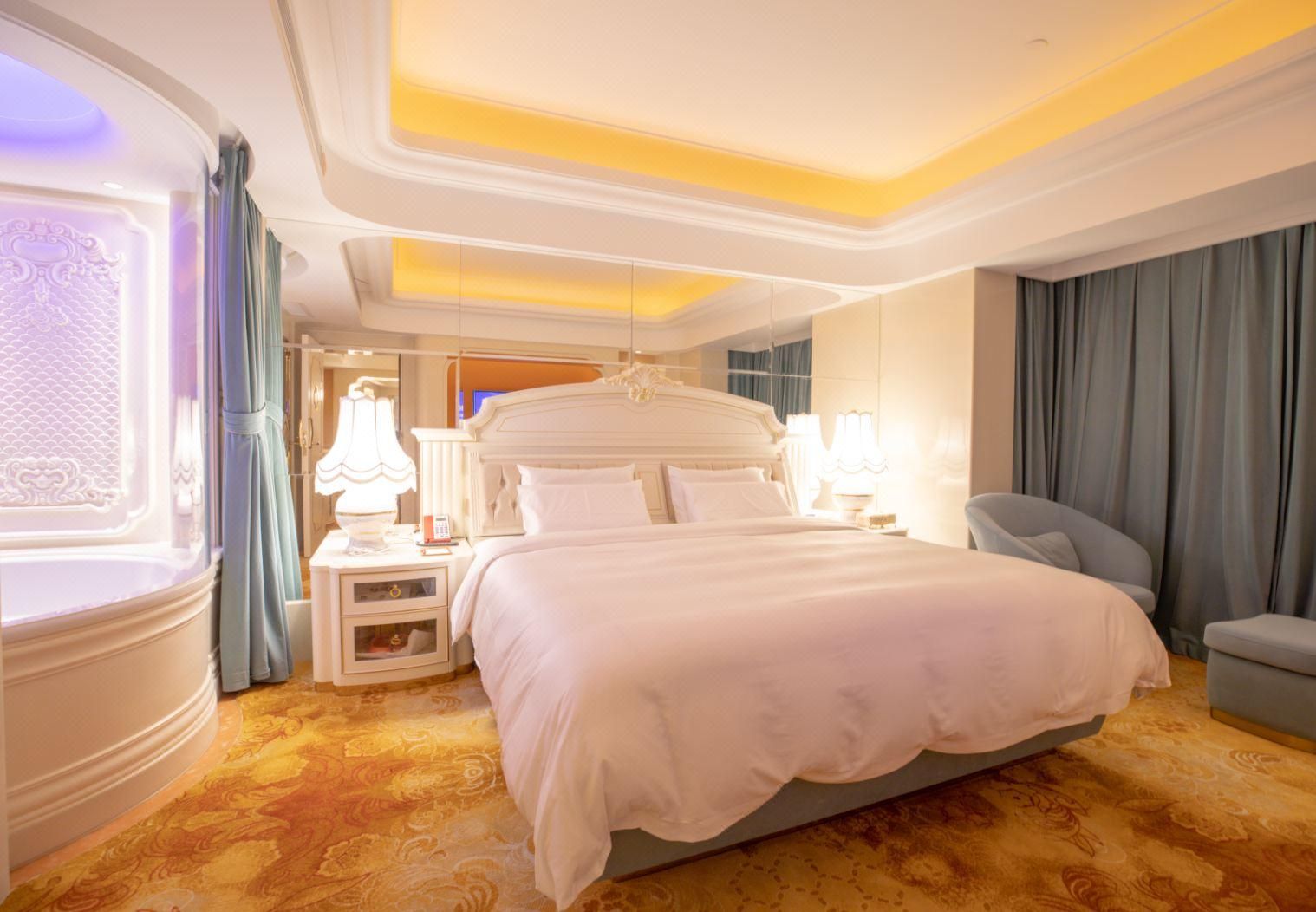 Habitación de hotel con una cama grande, mesitas de noche, una silla y un adorno en la pared.