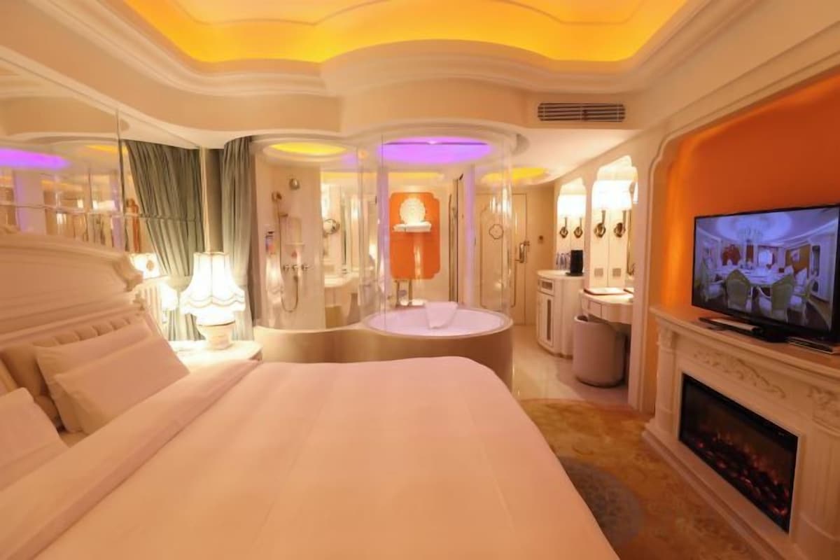 A hotel room with a large bed, a television, a fireplace, and a circular seating area.