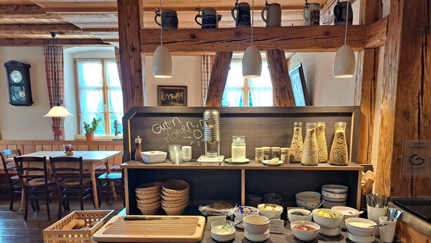 A rustic café interior with wooden beams, a chalkboard menu, and various food items displayed on shelves. - Landgasthof Rössle - Beim Kräuterwirt (Stiefenhofen)