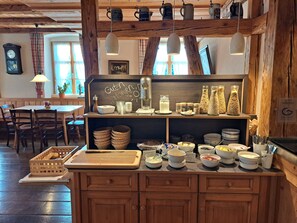 A rustic café interior with wooden beams, a chalkboard menu, and various food items displayed on shelves. - Landgasthof Rössle - Beim Kräuterwirt (Stiefenhofen)