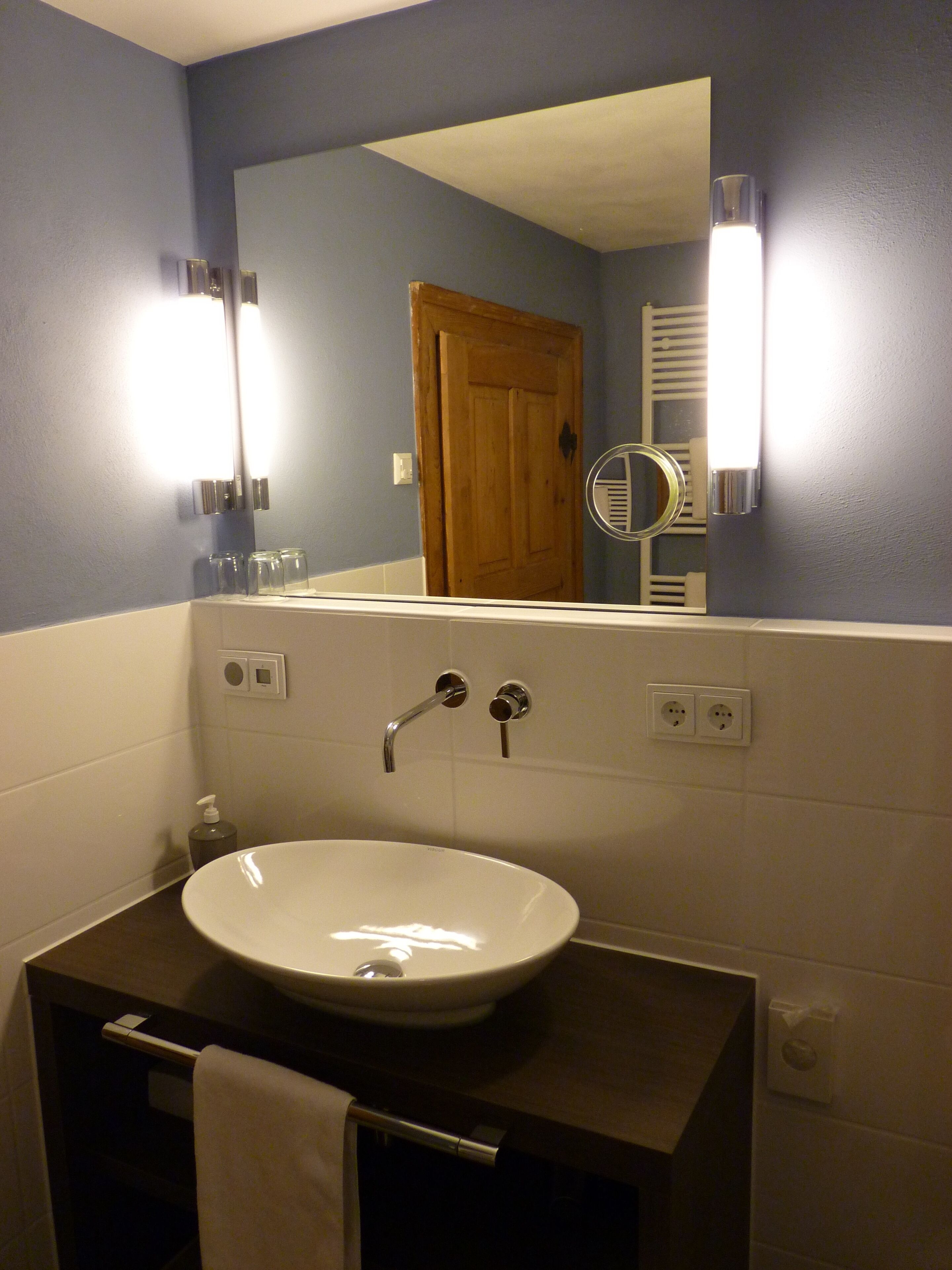 A bathroom with a white sink, a mirror, and a door.