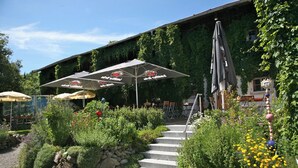 A restaurant with outdoor seating, stone steps, and a garden with various plants and flowers. - Landgasthof Rössle - Beim Kräuterwirt (Stiefenhofen)