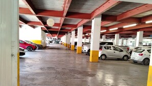 Un aparcamiento de varios niveles con suelos de hormigón y pilares rojo y blanco.