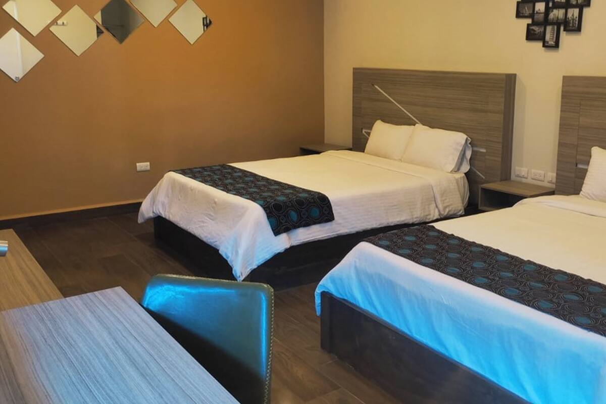 Habitación de hotel con dos camas, un escritorio y una silla.