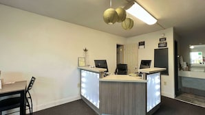 A reception desk with two computer monitors, a framed picture, and a decorative plant. - Super 8 by Wyndham Sulphur South (Sulphur)