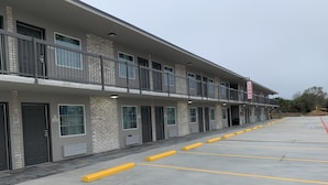 A multi-story hotel with a ground-level lobby, multiple rooms on the upper floors, and a parking lot with yellow bollards. - Super 8 by Wyndham Sulphur South (Sulphur)
