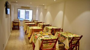 A dining area with multiple tables and chairs, arranged in rows, with a view of the outside through a large window. - Hotel Express (Maldonado)