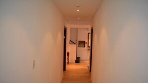 A narrow, well-lit hallway with wooden flooring and white walls, leading to a staircase and a framed picture on the wall. - Hotel Express (Maldonado)