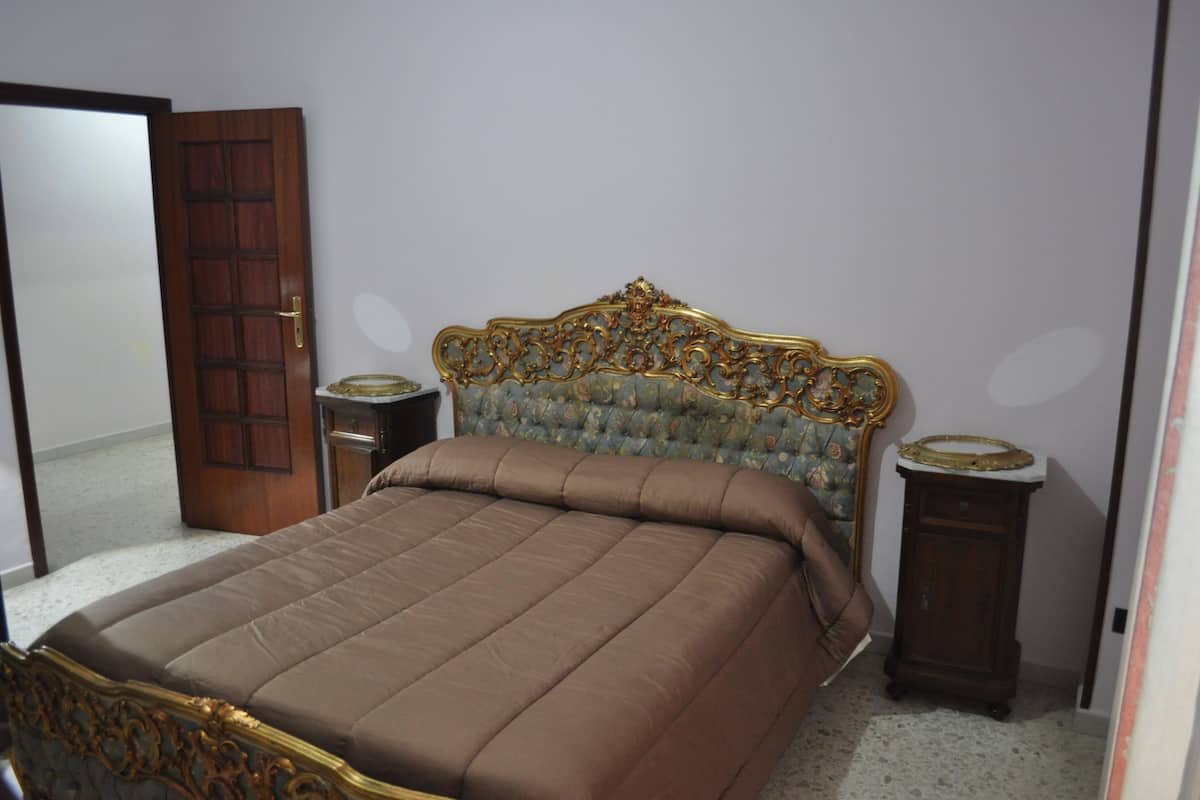 A bedroom with a large bed, a wooden door, and two bedside tables.