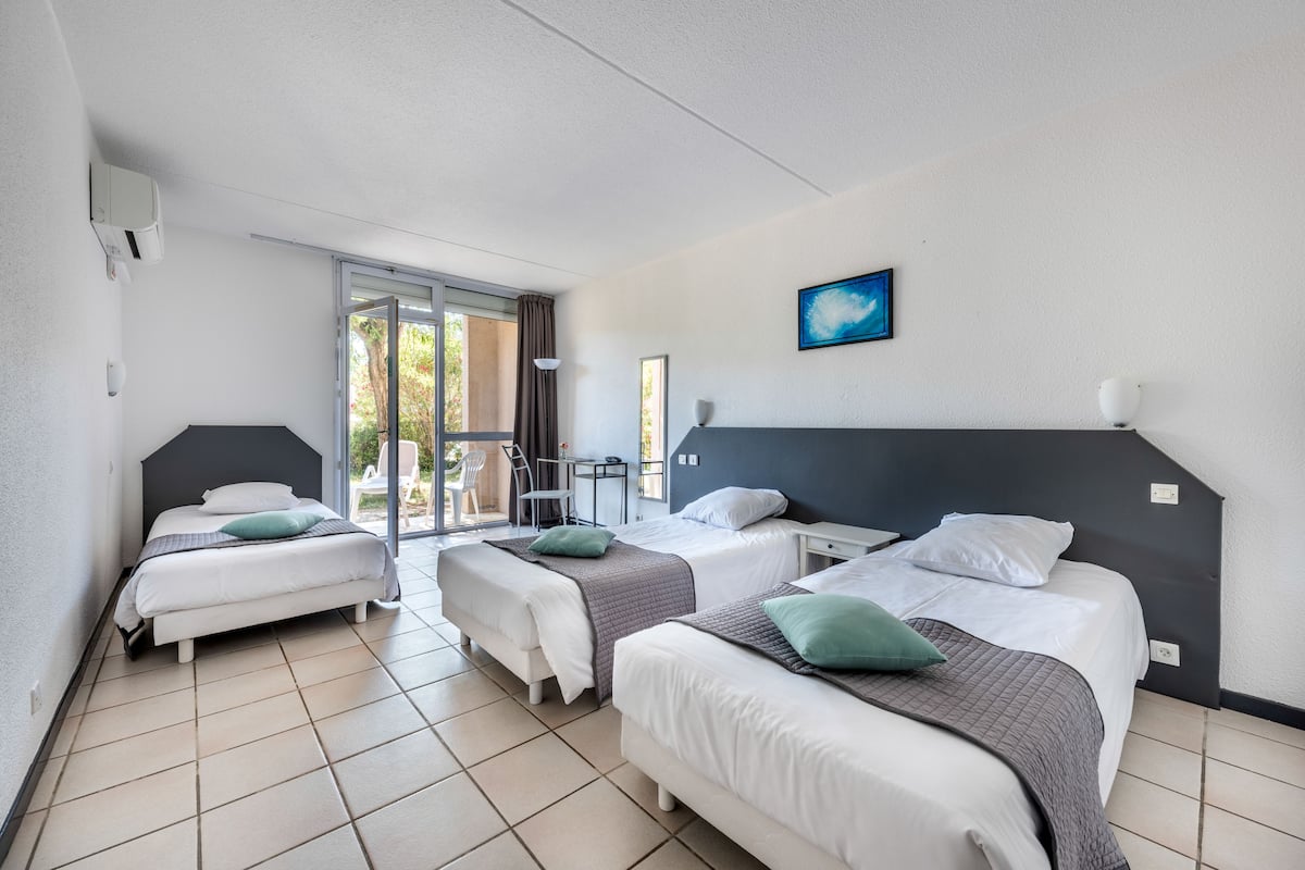 Une chambre d’hôtel avec deux lits, une grande fenêtre et une vue sur l’extérieur.
