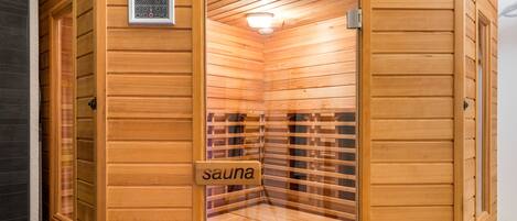 Uma sauna com paredes de madeira, um painel de controle e uma placa indicando sua função.