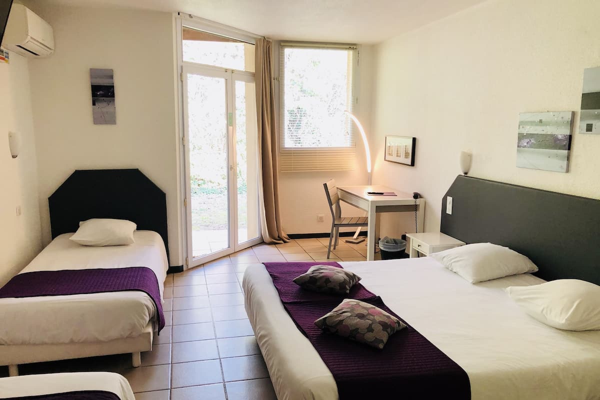 Une chambre d’hôtel avec deux lits, un bureau et une chaise.