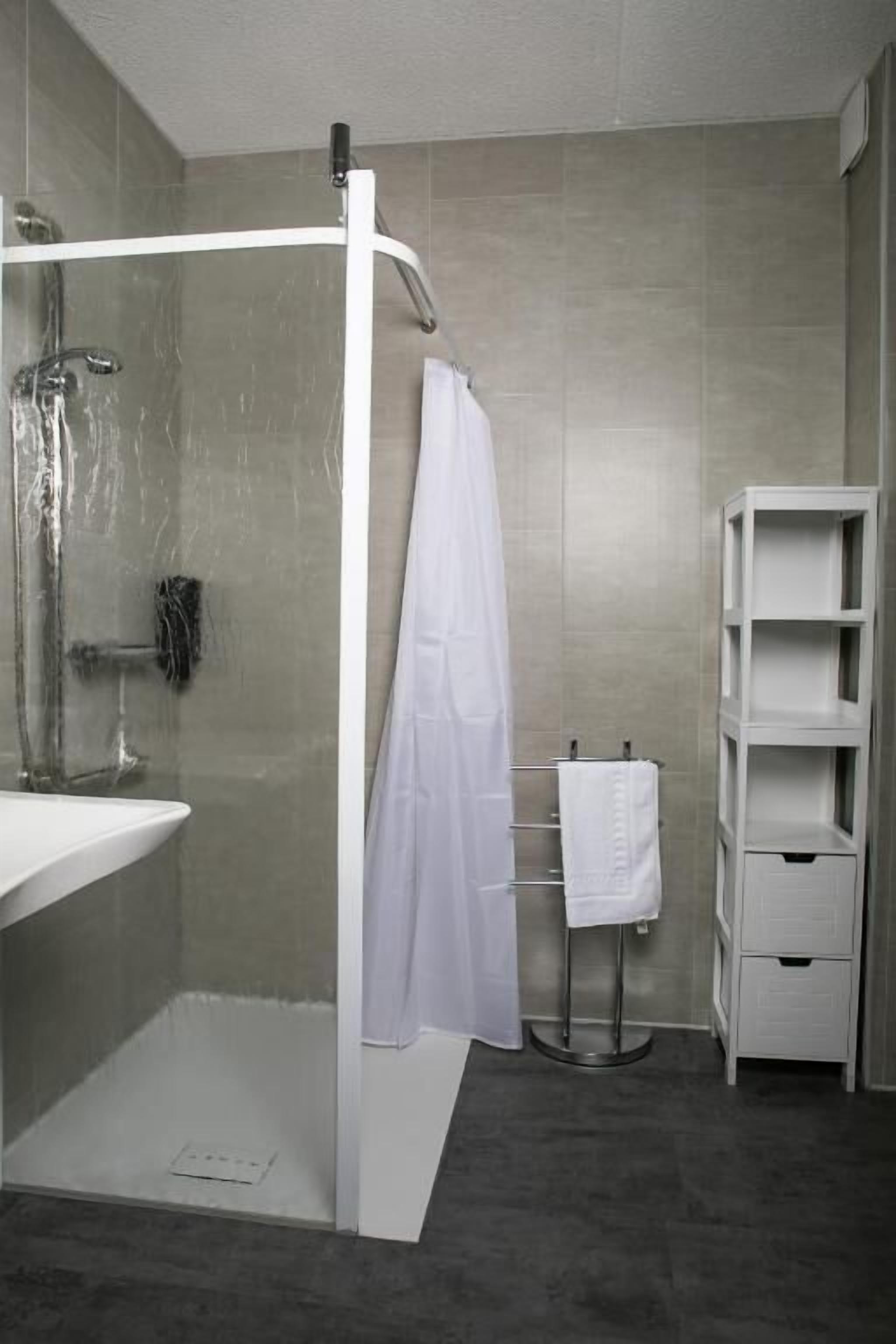 A modern bathroom with a glass-enclosed shower, a white sink, and a built-in shelf unit.