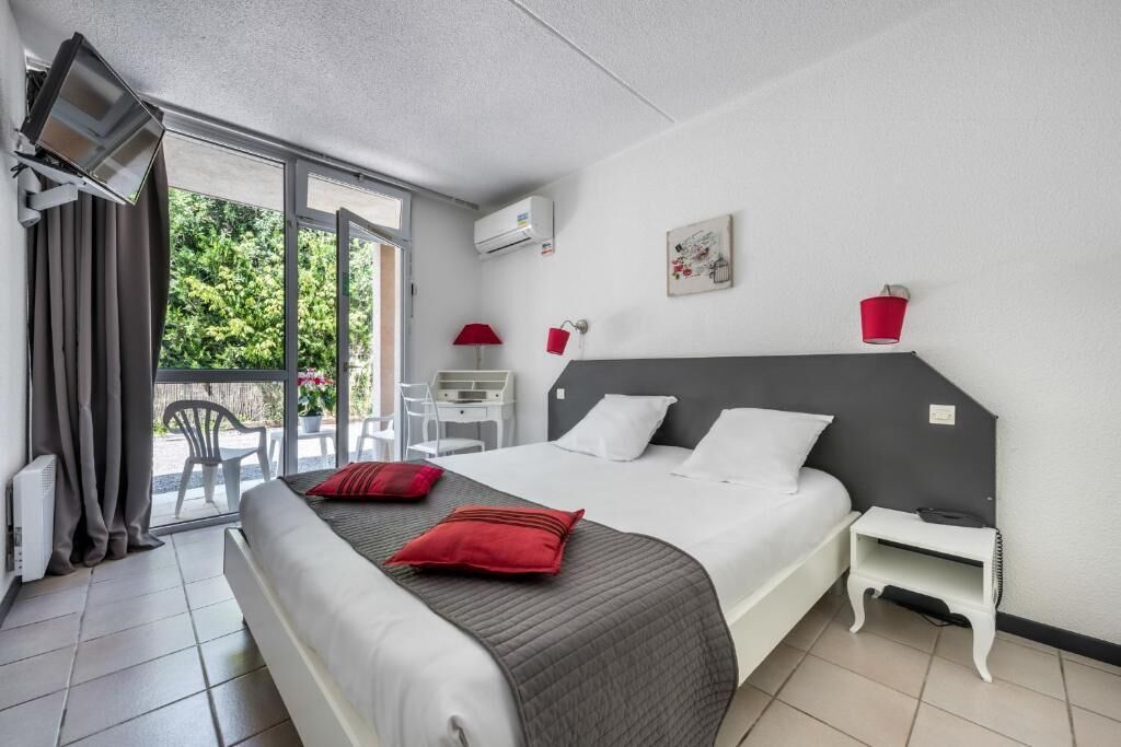 Una habitación de hotel con una cama, un escritorio, una silla y un balcón.