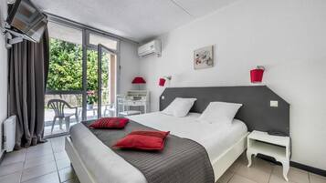 Una habitación de hotel con una cama, un escritorio, una silla y un balcón.