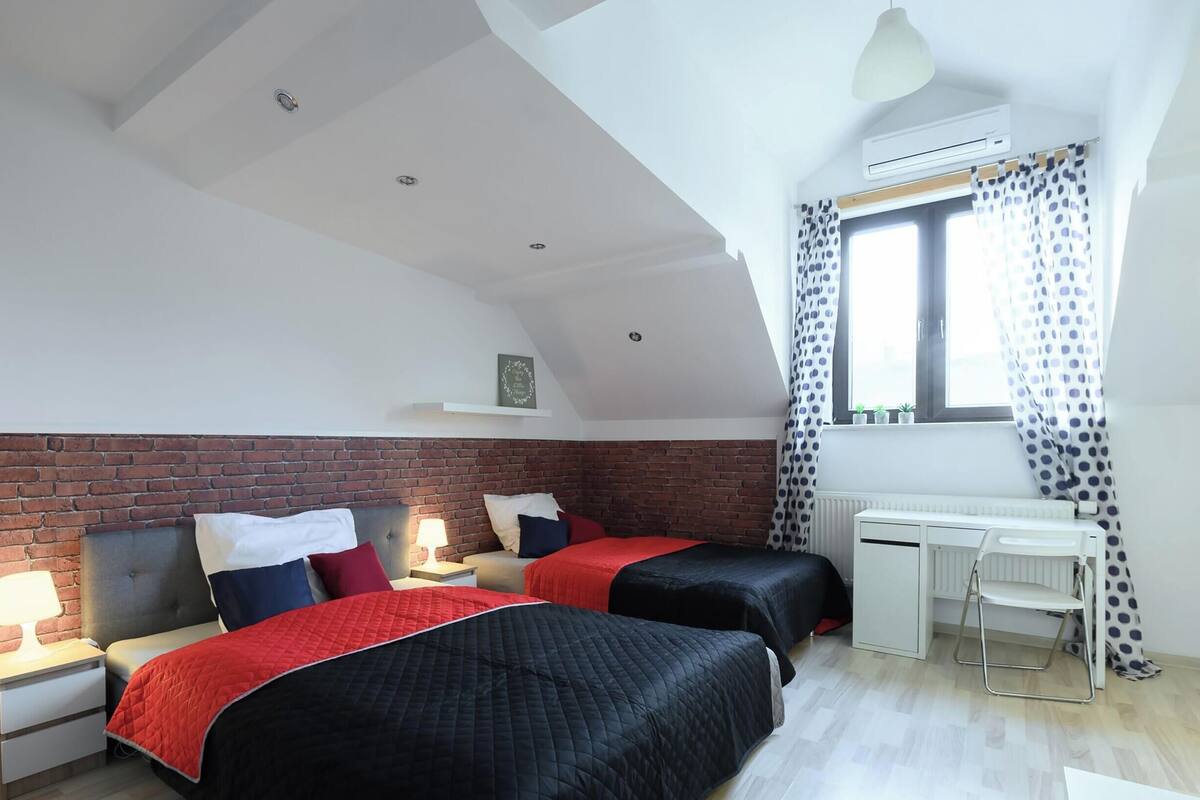 Un dormitorio con dos camas, un escritorio, un radiador y una ventana con cortinas.