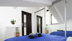 A modern hotel room with a large bed, a mirror, and a small desk with a plant. - Station Apartments Kątowa 11 Krakow (Kraków)