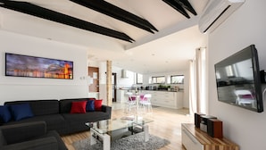 A modern living room with a dark sofa, glass coffee table, and a flat-screen TV. - Station Apartments Kątowa 11 Krakow (Kraków)